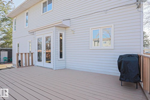 Spacious outdoor deck with a light-toned finish, featuring a wooden railing and direct access to the interior via double glass-paneled doors - 2433 89 Street, Edmonton, AB - Outdoor With Deck Patio Veranda With Exterior