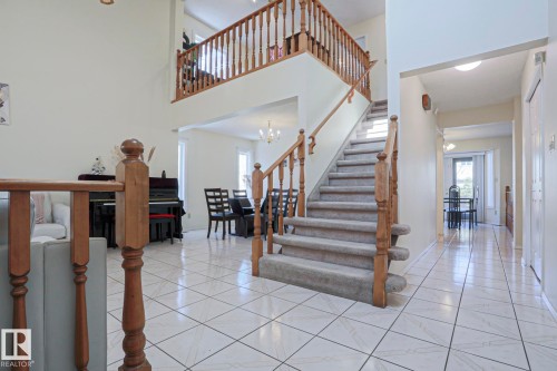 Two-story foyer featuring a grand staircase with wood railings and carpeted treads - 2433 89 Street, Edmonton, AB - Indoor Photo Showing Other Room