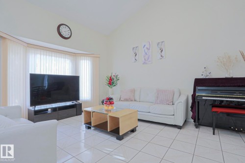 Spacious living area featuring a vaulted ceiling and bay window with vertical blinds - 2433 89 Street, Edmonton, AB - Indoor Photo Showing Other Room