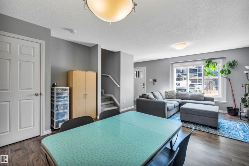 Open-concept living space featuring wood-finish flooring, a large window, and light grey walls - 2424 Wonnacott Crest, Edmonton, AB - Indoor Photo Showing Other Room
