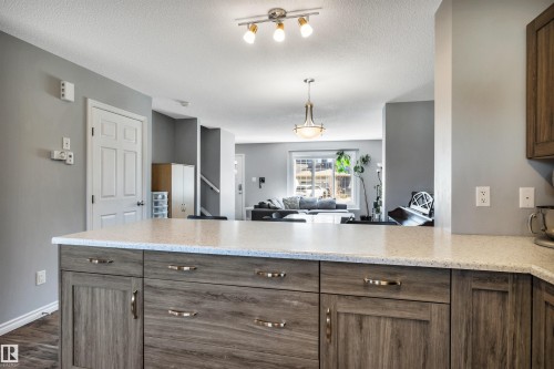 Kitchen island featuring a light-toned countertop and wood-finish cabinetry with brass hardware - 2424 Wonnacott Crest, Edmonton, AB - Indoor Photo Showing Kitchen