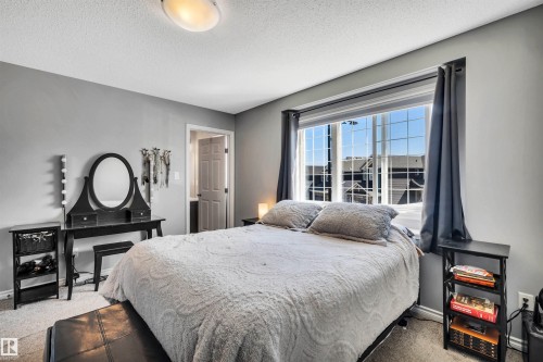 Carpeted room featuring a large multi-pane window with dark drapery - 2424 Wonnacott Crest, Edmonton, AB - Indoor Photo Showing Bedroom