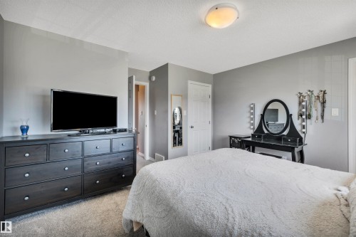 Carpeted bedroom with a neutral color palette, featuring a ceiling-mounted light fixture, white interior doors, and a built-in closet - 2424 Wonnacott Crest, Edmonton, AB - Indoor Photo Showing Bedroom