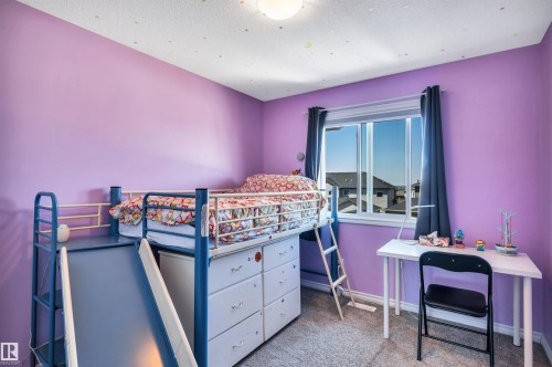 Room with purple walls, a large window with dark curtains, and light-colored carpet flooring - 2424 Wonnacott Crest, Edmonton, AB - Indoor Photo Showing Bedroom