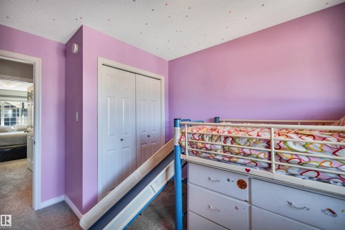 Room with lavender walls featuring a built-in closet with bi-fold doors - 2424 Wonnacott Crest, Edmonton, AB - Indoor Photo Showing Bedroom