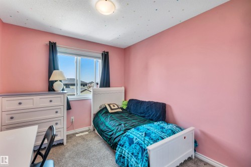 Room featuring a window with dark curtains, light pink walls, a flush-mount ceiling light, and gray carpet flooring - 2424 Wonnacott Crest, Edmonton, AB - Indoor Photo Showing Bedroom