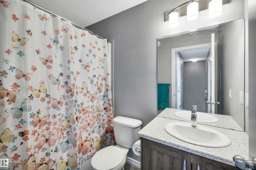 Bathroom featuring a vanity with a white oval sink, speckled countertop, and wood-finish cabinetry - 2424 Wonnacott Crest, Edmonton, AB - Indoor Photo Showing Bathroom