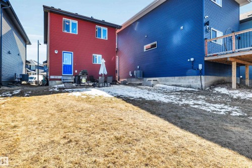 Expansive yard space featuring a partial concrete patio and direct access to the red-sided structure - 2424 Wonnacott Crest, Edmonton, AB - Outdoor With Exterior