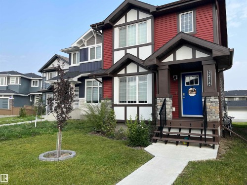 Red and white exterior featuring a bold blue entry door with transom window - 2424 Wonnacott Crest, Edmonton, AB - Outdoor With Facade