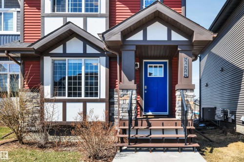 Exterior facade featuring a bright blue entry door, stone accents, and a covered porch - 2424 Wonnacott Crest, Edmonton, AB - Outdoor With Facade