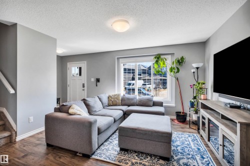 Open-concept living area featuring wood-finish flooring, light gray wall paint, and a white ceiling - 2424 Wonnacott Crest, Edmonton, AB - Indoor Photo Showing Living Room