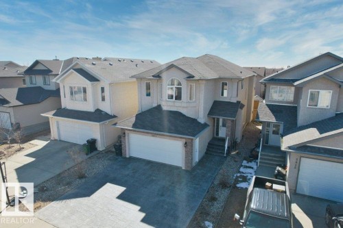 Stucco exterior residence featuring a prominent arched window, integrated double garage, and a brick paver driveway - 5871 166 Avenue, Edmonton, AB - Outdoor With Facade