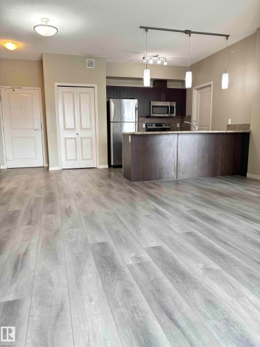 Open-concept living space featuring wood-finish flooring throughout - 408 111 Ambelside Drive Sw, Edmonton, AB - Indoor Photo Showing Kitchen