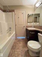 Bathroom featuring a white bathtub and shower combination, dark wood-finish vanity with an integrated sink, extended countertop, and a large wall-mounted mirror - 
