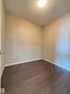Neutral painted walls with white baseboards and dark wood-finish flooring - 