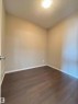 Neutral painted walls with white baseboards and dark wood-finish flooring - 408 111 Ambelside Drive Sw, Edmonton, AB  - Indoor Photo Showing Other Room 