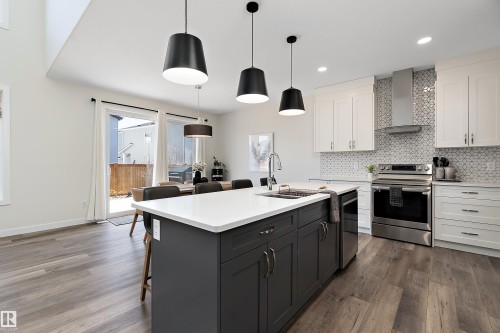 Modern kitchen featuring a large central island with dark cabinetry and a white countertop - 591 Boulder Wynd, Leduc, AB - Indoor Photo Showing Kitchen With Upgraded Kitchen