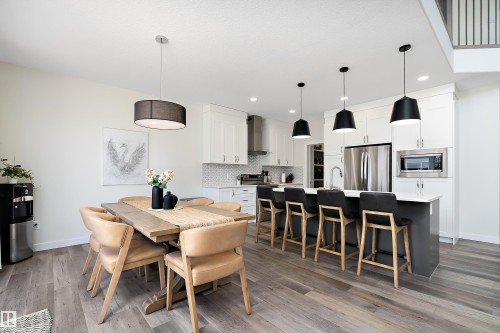 Open-concept kitchen and dining area featuring light-toned wood-finish flooring - 591 Boulder Wynd, Leduc, AB - Indoor Photo Showing Dining Room
