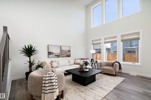 Vaulted living area featuring high ceilings, upper and lower window banks, and wood-finish flooring - 591 Boulder Wynd, Leduc, AB - Indoor Photo Showing Living Room