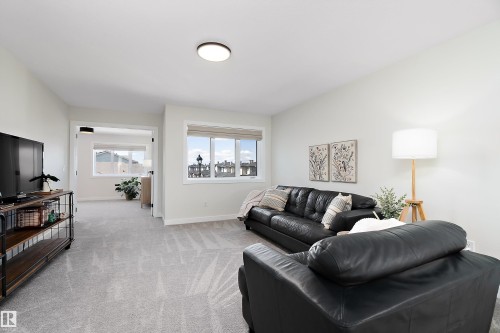 Spacious carpeted room featuring multiple windows, white baseboards, and a neutral wall palette - 591 Boulder Wynd, Leduc, AB - Indoor Photo Showing Living Room