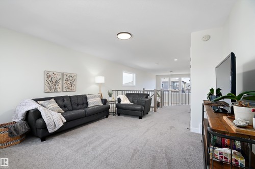 Spacious carpeted landing featuring white walls, a white railing with wood accents, and recessed lighting - 591 Boulder Wynd, Leduc, AB - Indoor Photo Showing Living Room