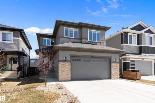 Contemporary exterior featuring multi-toned siding, stone accents, and a dual-panel garage door - 591 Boulder Wynd, Leduc, AB - Outdoor With Facade