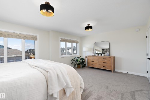 Spacious room featuring light gray carpet flooring, white painted walls, and two large windows with blinds - 591 Boulder Wynd, Leduc, AB - Indoor Photo Showing Bedroom
