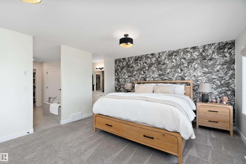 Bedroom featuring a statement accent wall with a botanical pattern - 591 Boulder Wynd, Leduc, AB - Indoor Photo Showing Bedroom