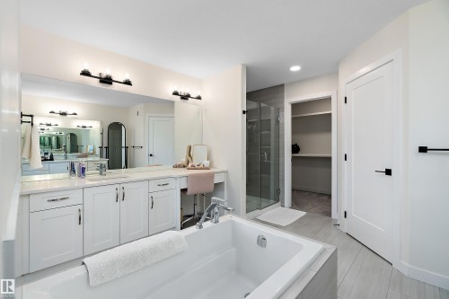 Contemporary bathroom featuring a built-in tub, dual sink vanity with white cabinetry, a glass-enclosed shower, and a dedicated vanity area - 591 Boulder Wynd, Leduc, AB - Indoor Photo Showing Bathroom