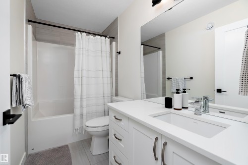 Bathroom featuring a full vanity with an integrated sink, polished chrome faucet, and a large mirror - 591 Boulder Wynd, Leduc, AB - Indoor Photo Showing Bathroom