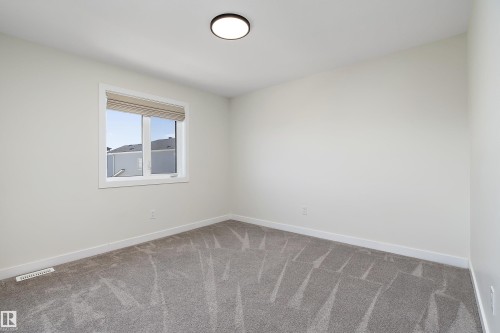 Bedroom featuring light-colored walls, gray patterned carpet, and a window with a neutral-toned blind - 591 Boulder Wynd, Leduc, AB - Indoor Photo Showing Other Room