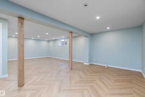 Spacious room featuring light wood-finish flooring in a herringbone pattern, recessed ceiling lighting, and a neutral wall color - 591 Boulder Wynd, Leduc, AB - Indoor Photo Showing Other Room