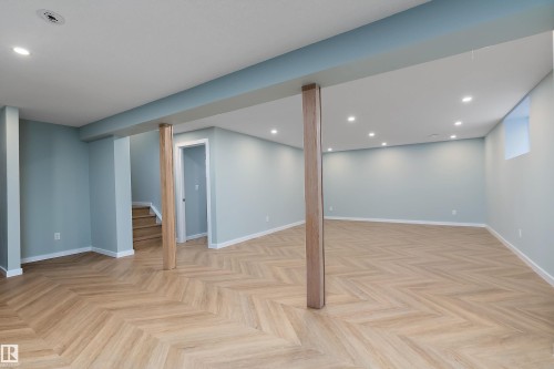 Expansive finished lower level featuring light wood-finish flooring in a herringbone pattern, recessed lighting, and light blue wall tones - 591 Boulder Wynd, Leduc, AB - Indoor Photo Showing Other Room