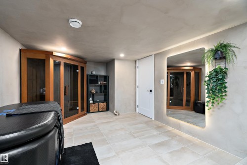 Dedicated wellness space featuring a wood-panel sauna with glass doors, light-toned tile flooring, and smooth wall finishes - 591 Boulder Wynd, Leduc, AB - Indoor Photo Showing Other Room