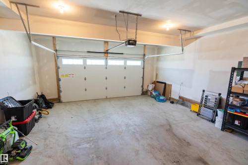 Two-car garage featuring a concrete floor, automatic garage door opener, and multiple overhead light fixtures - 591 Boulder Wynd, Leduc, AB - Indoor Photo Showing Garage