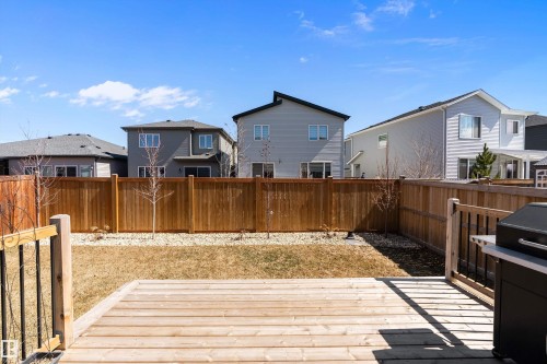 Outdoor deck with natural wood planks and black balusters, opening onto a backyard area - 591 Boulder Wynd, Leduc, AB - Outdoor With Deck Patio Veranda With Exterior