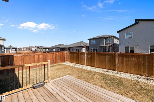 Rear yard featuring a wooden privacy fence, a wood-finish deck, and a grass lawn - 591 Boulder Wynd, Leduc, AB - Outdoor With Exterior