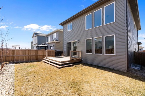 Rear exterior with a multi-level wood deck, sliding glass door, and multiple large windows - 591 Boulder Wynd, Leduc, AB - Outdoor With Deck Patio Veranda With Exterior