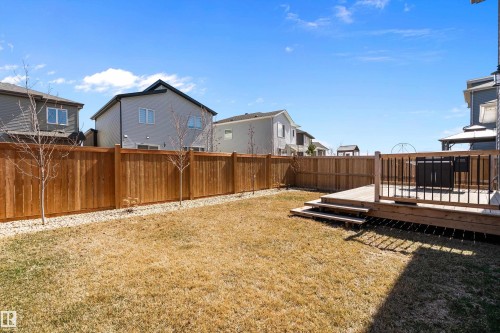 Spacious backyard featuring a multi-level wooden deck with balustrade, wooden privacy fencing, and a gravel border - 591 Boulder Wynd, Leduc, AB - Outdoor