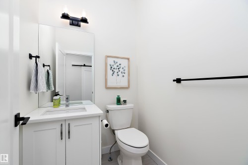 Bathroom featuring a white vanity with integrated sink, a rectangular mirror, and matte black fixtures - 591 Boulder Wynd, Leduc, AB - Indoor Photo Showing Bathroom