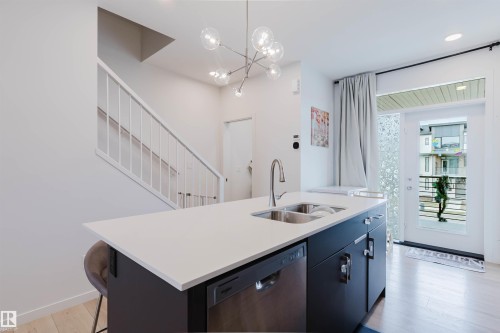 Kitchen island with a white countertop and integrated double sink - 3288 Keswick Way, Edmonton, AB - Indoor Photo Showing Kitchen With Double Sink