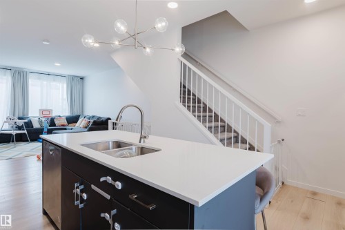 Kitchen island with a double basin stainless steel sink, a pull-down faucet, and white countertop - 3288 Keswick Way, Edmonton, AB - Indoor Photo Showing Kitchen With Double Sink