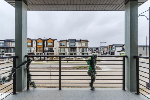 Covered balcony featuring a textured concrete floor, durable black metal railings, and sturdy support columns - 3288 Keswick Way, Edmonton, AB - Outdoor