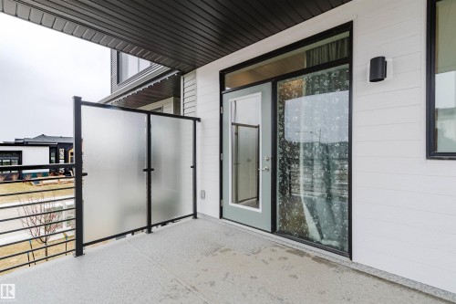 Private balcony featuring a frosted glass divider, black metal railings, and a textured concrete floor - 3288 Keswick Way, Edmonton, AB - Outdoor With Exterior