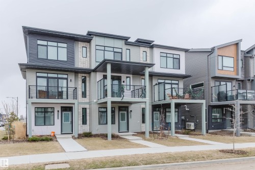 Modern townhome exterior featuring multi-toned siding, a flat roofline, and multiple balconies with dark-framed railings - 3288 Keswick Way, Edmonton, AB - Outdoor With Balcony With Facade