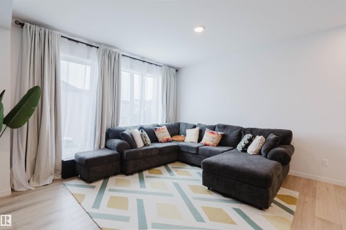 Bright living area featuring wood-finish flooring, recessed lighting, and large windows with privacy sheers - 3288 Keswick Way, Edmonton, AB - Indoor Photo Showing Living Room