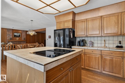 Kitchen featuring a tiled island with a built-in cooktop, light wood-finish cabinetry, black appliances, a tiled backsplash, and recessed lighting - 848 Wheeler Road W, Edmonton, AB - Indoor Photo Showing Kitchen