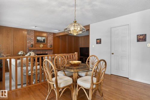 Hardwood flooring extending into an adjacent space featuring a brick fireplace - 848 Wheeler Road W, Edmonton, AB - Indoor Photo Showing Dining Room