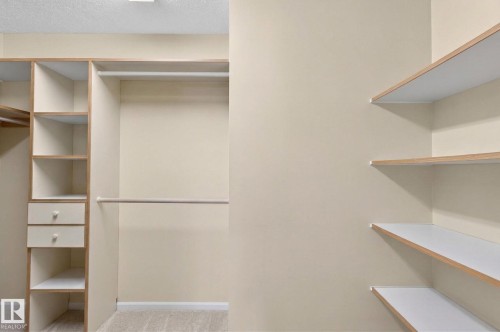 Custom closet system with built-in shelving, hanging rods, and integrated drawers with round knobs - 848 Wheeler Road W, Edmonton, AB - Indoor With Storage