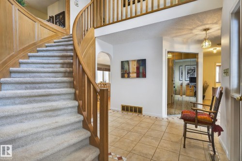 Two-story foyer featuring a curved wood staircase with carpeted treads, tile flooring, and a mirrored closet door - 848 Wheeler Road W, Edmonton, AB - Indoor Photo Showing Other Room
